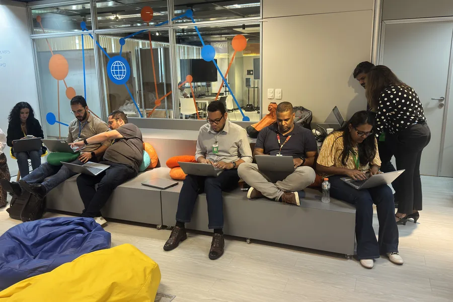 Participantes de uma capacitação trabalhando em laptops numa sala de inovação